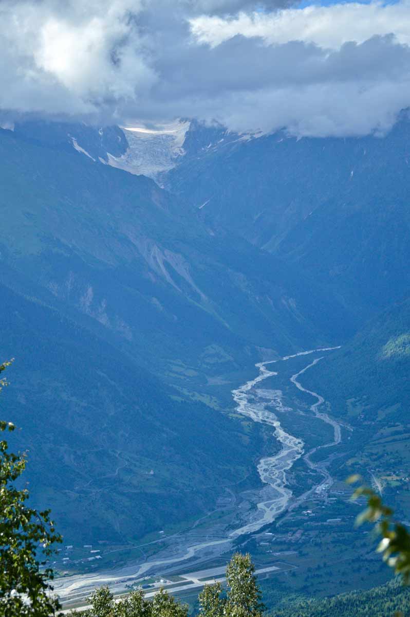 Glaciär och flodfåra djupt bland bergen i Svaneti